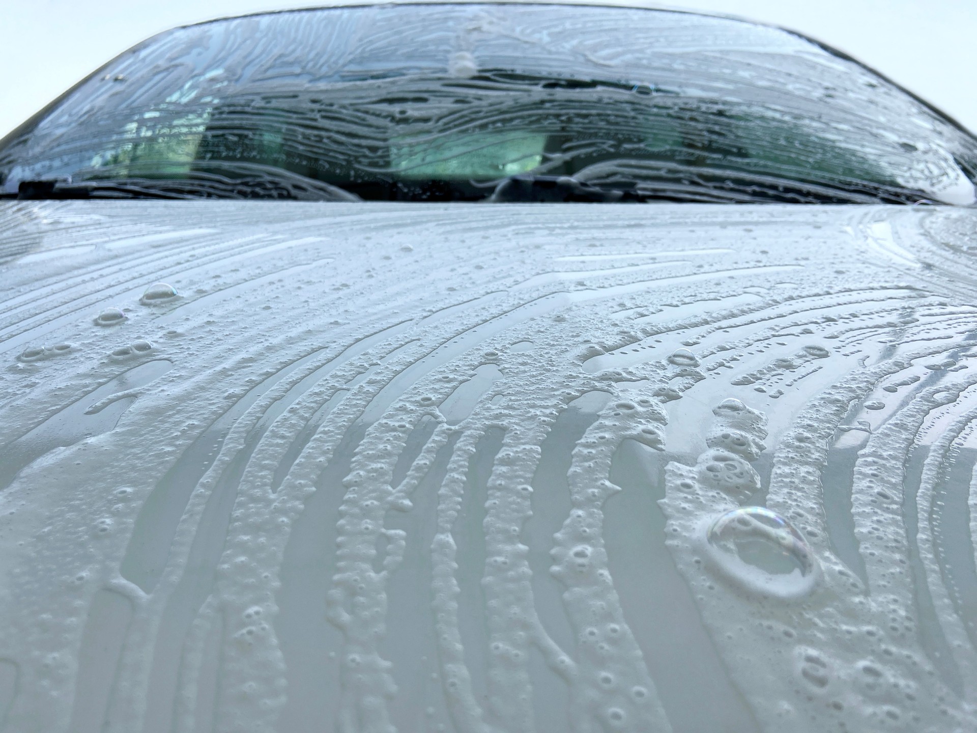 Car washing, front view car with soap sud
