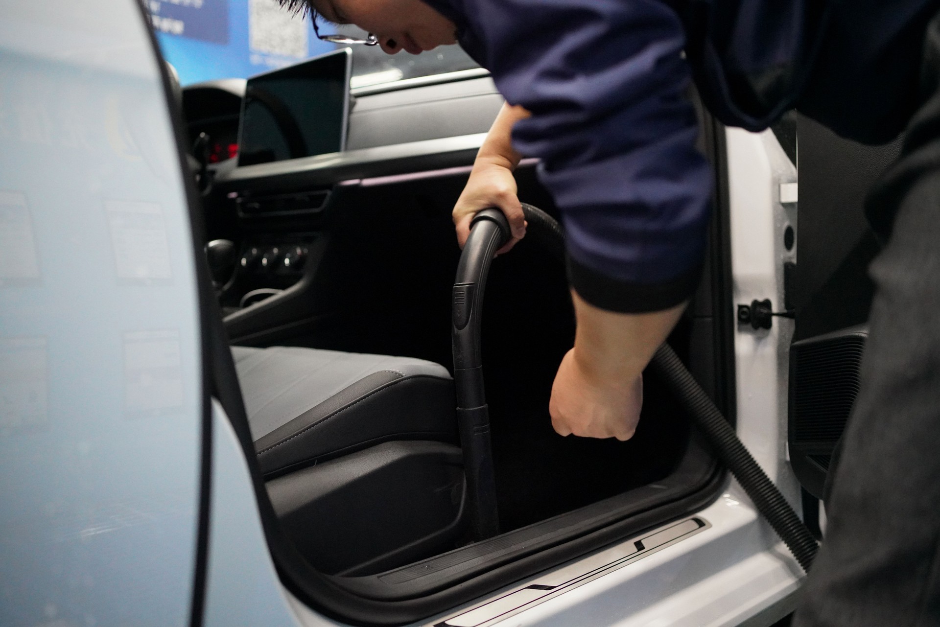 Man cleaning car seat with vacuum cleaner